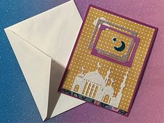 an origami envelope with a card inside it and a paper cut out to look like a mosque