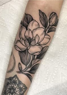 a black and white flower tattoo on the arm