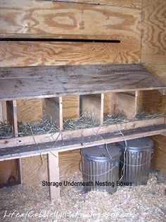 the inside of a chicken coop with hay and two buckets on top of it