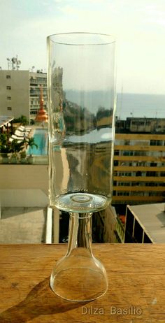 a clear glass sitting on top of a wooden table next to a cityscape