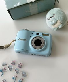 a blue camera sitting on top of a table next to a stuffed animal and some stickers