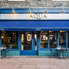 the outside of a restaurant with blue awnings and tables in front of it