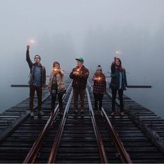 a group of people standing on top of a train track holding sparklers in their hands