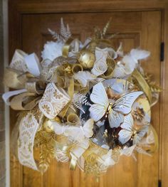 a close up of a wreath on a door with gold and white decorations around it