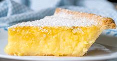 a slice of lemon pie on a plate with powdered sugar over it and a blue towel in the background