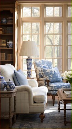 a living room with blue and white furniture in front of a large window filled with bookshelves