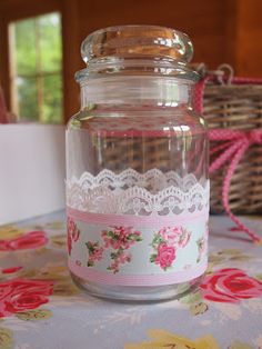 a glass jar sitting on top of a table covered in pink and white laces