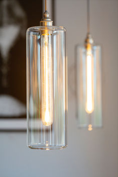 two clear glass pendant lights hanging from a ceiling