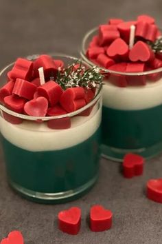 two small cups filled with marshmallows on top of a gray table next to red candies