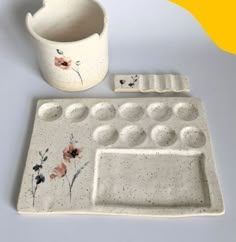 a white cup and tray with flowers painted on it