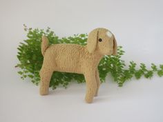 a toy dog standing next to some green plants