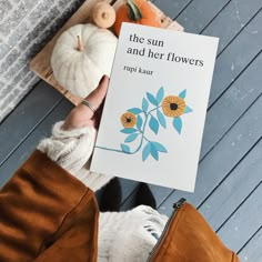 a person holding up a book about the sun and her flowers