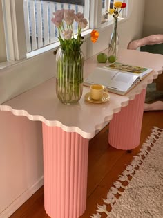 a vase with flowers sitting on top of a table next to a book and cup