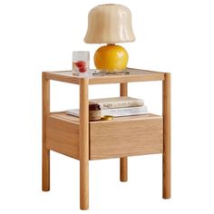 a wooden table with a lamp on top of it next to some books and an orange