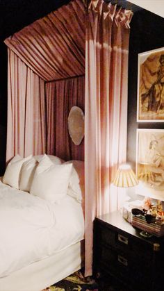 a bed with white sheets and pink drapes