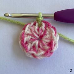 the crochet ball is being worked on with a knitting needle and yarn hook