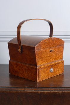 a wooden box sitting on top of a brown table next to a white wall and floor