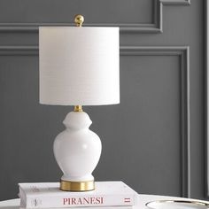 a white lamp sitting on top of a table next to two books and a cup