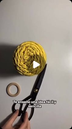 someone is using scissors to cut the rope off of a ball of yarn that's being held in front of them