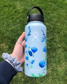 a hand holding a water bottle with blue flowers on it