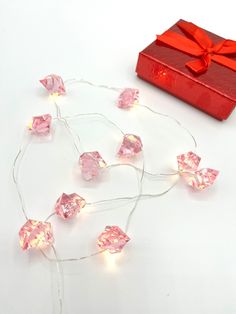 a red box and string lights on a white surface next to a red present bag