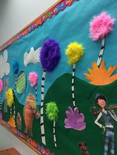 a bulletin board decorated with colorful pom - poms on it's side