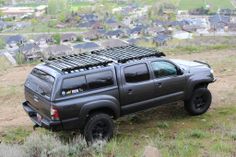 a black truck parked on top of a grass covered field