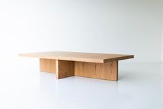 a wooden table sitting on top of a white floor in front of a white wall