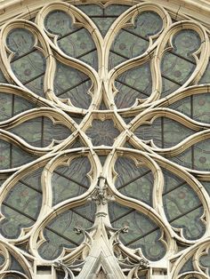 an ornate stained glass window on the side of a building with decorative carvings and arches