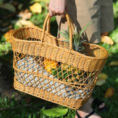 a person holding a wicker basket with pineapples in it on the grass