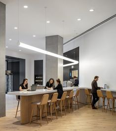 people are sitting at the counter in an open room with wood floors and white walls