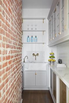 a kitchen with white cabinets and brick walls