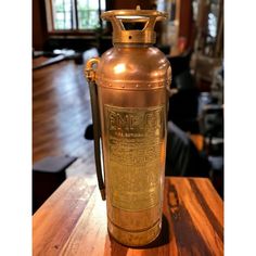 an old brass fire extinguisher sitting on a wooden table