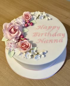 a white birthday cake with pink flowers and the words happy birthday nanna on it