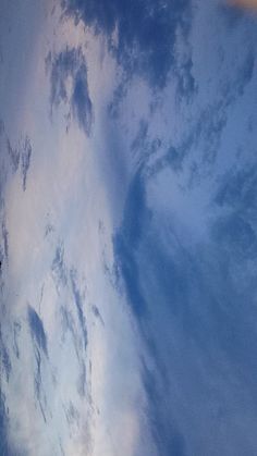 an airplane is flying high in the sky with clouds and blue skies behind it, as seen from below