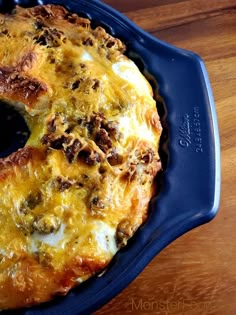 a cheese and sausage ring sitting on top of a blue pan filled with melted cheese