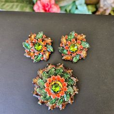 Vintage Judy Lee Jewels Rhinestone Brooch & Earring Set Beautiful Set By Judy Lee Featuring Brown, Green And Brilliant Orange Rhinestones In A Tiered, Pinwheel Shape And Centered By A Watermelon Heliotrope In Orange And Green Tones, All Prong Set Into Shiny Gold Tone Metal. Brooch Measures 2 1/4 Inches Across And Has A Secure Pin Back Closure. Signed Judy Lee On The Back. Matching Clip Back Earrings Measure 1 1/2 Inches Across And Have Good Tension On The Clips. Signed Judy Lee On The Back Of Each Clip. In Excellent Vintage Condition. Metal Brooch, Orange And Green, Green Tones, Rhinestone Brooches, Pin Backs, Gold Tone Metal, Green And Orange, Prong Setting, Earring Set