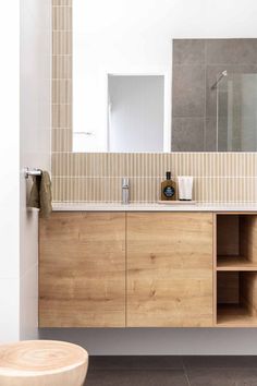 a bathroom with a wooden cabinet, mirror and stool in front of the counter top