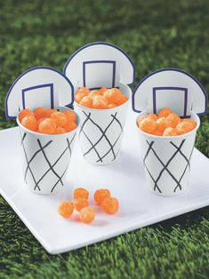 four buckets filled with orange candies sitting on top of a white square plate