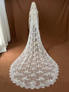 the back of a white wedding dress on display in front of a brown backdrop with curtains