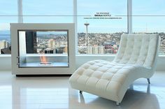 a white chair sitting in front of a window with a view of the city below