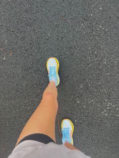 a person wearing blue and yellow shoes standing in the middle of a road with their feet up