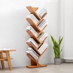 a tall wooden book stand with books on it's sides and a potted plant next to it