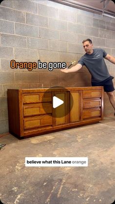 a man standing on top of a dresser next to a brick wall with the words orange be gone below it