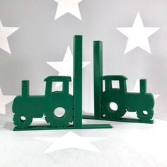 two green toy trucks sitting next to each other in front of stars on the wall