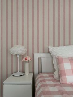 a bedroom with pink and white striped wallpaper, two nightstands and a bed