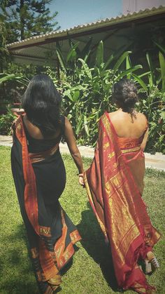 two women in sari walking down the grass carrying each other's hand and holding hands