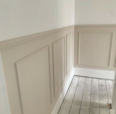 an empty room with white walls and wood flooring in the corner, along with wooden paneling