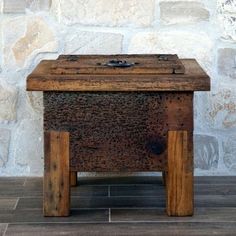 a wooden box sitting on top of a hard wood floor next to a brick wall