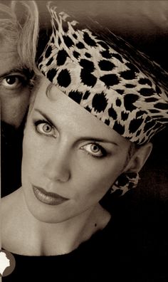 an old photo of a woman with a leopard print headband and man in the background